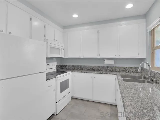 5978 Rancho Mission Road, Unit 264 San Diego, CA 92108 - Photo 6 of 22 a kitchen with granite countertop white cabinets and white appliances