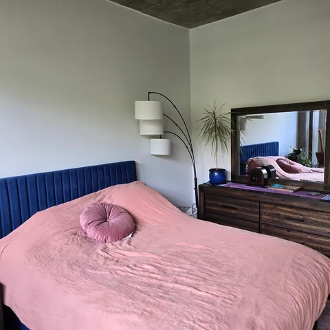 a bedroom with a bed and a potted plant on dresser