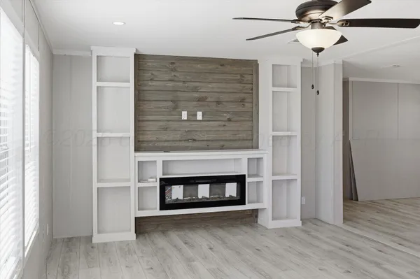 a view of an empty room with wooden floor fireplace and a window