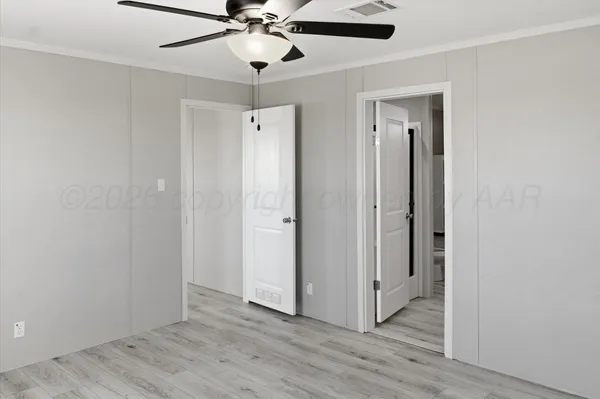 an empty room with wooden floor fan and windows