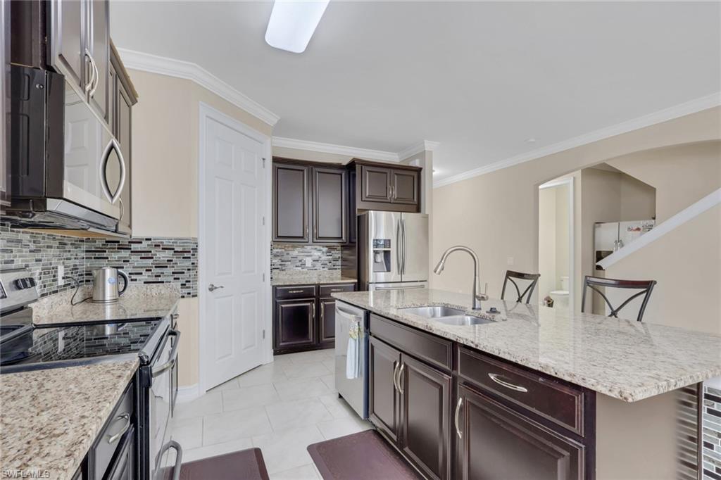 16309 Aberdeen Way Naples, FL 34110 - Photo 8 of 34 a kitchen with stainless steel appliances granite countertop a sink stove and cabinets
