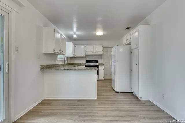 a kitchen with stainless steel appliances granite countertop a refrigerator a stove a sink and white cabinets