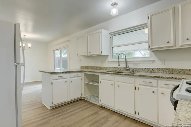 a kitchen with granite countertop white cabinets white appliances and sink