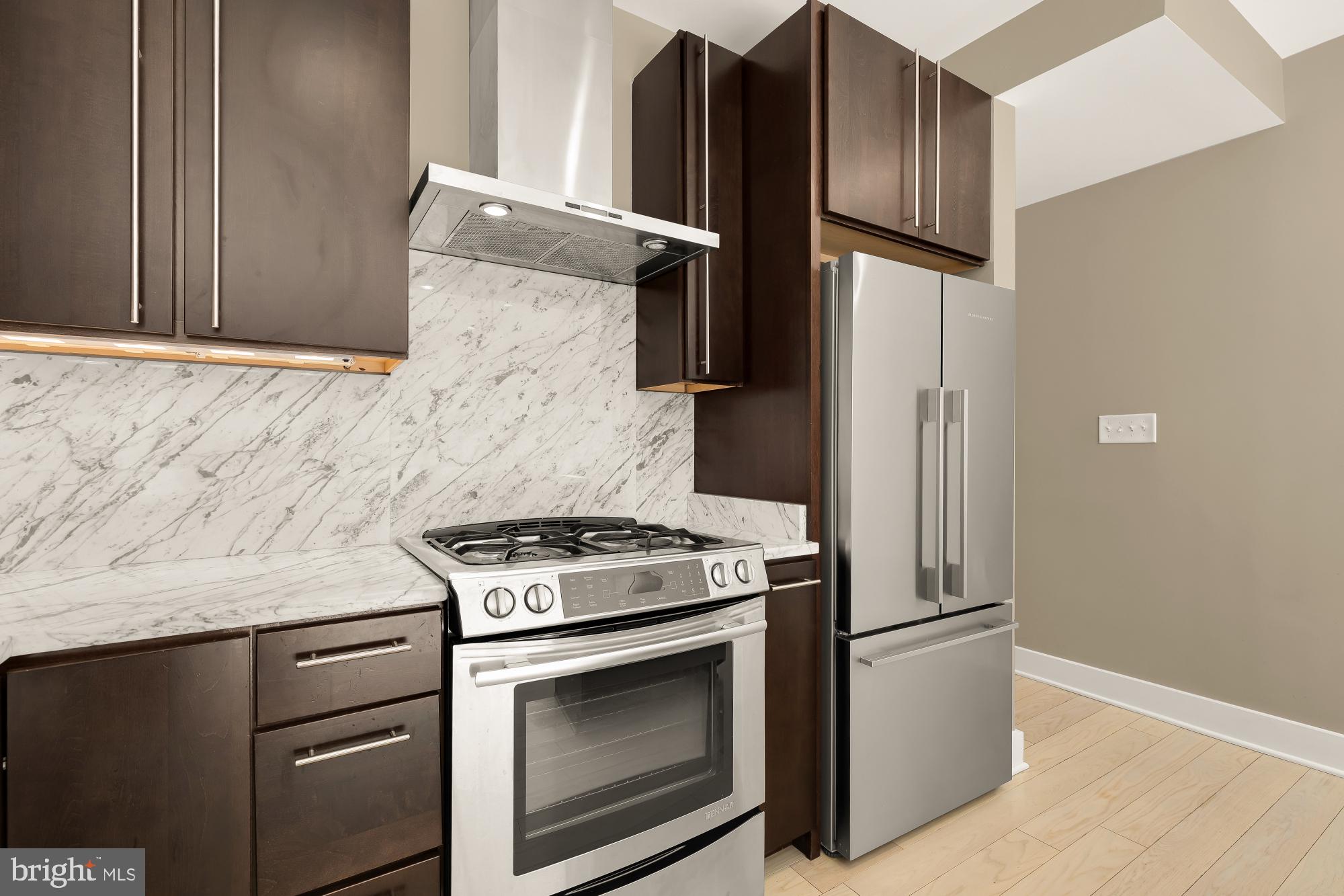 1634 14th Street Northwest, Unit 201 Washington, DC 20009 - Photo 8 of 24 a kitchen with granite countertop cabinets stainless steel appliances and wooden floor