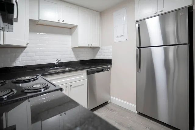 a kitchen with white cabinets and black appliances