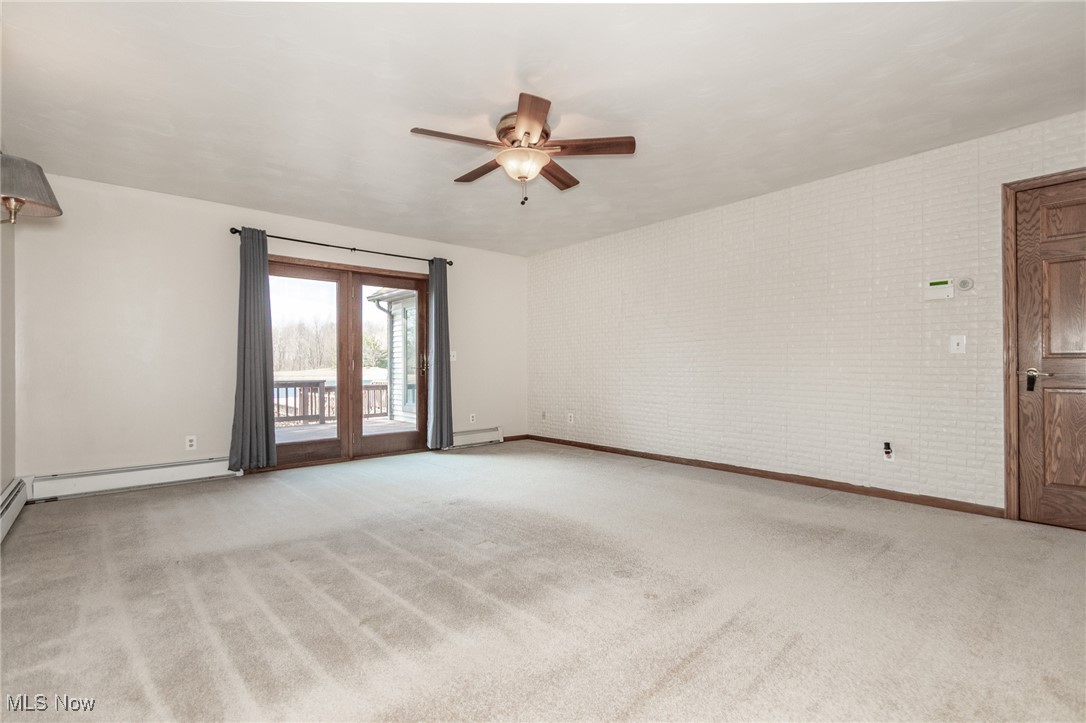 2866 South County Line Road Madison, OH 44057 - Photo 38 of 48 Unfurnished room featuring light carpet, brick wall, ceiling fan, and a baseboard heating unit