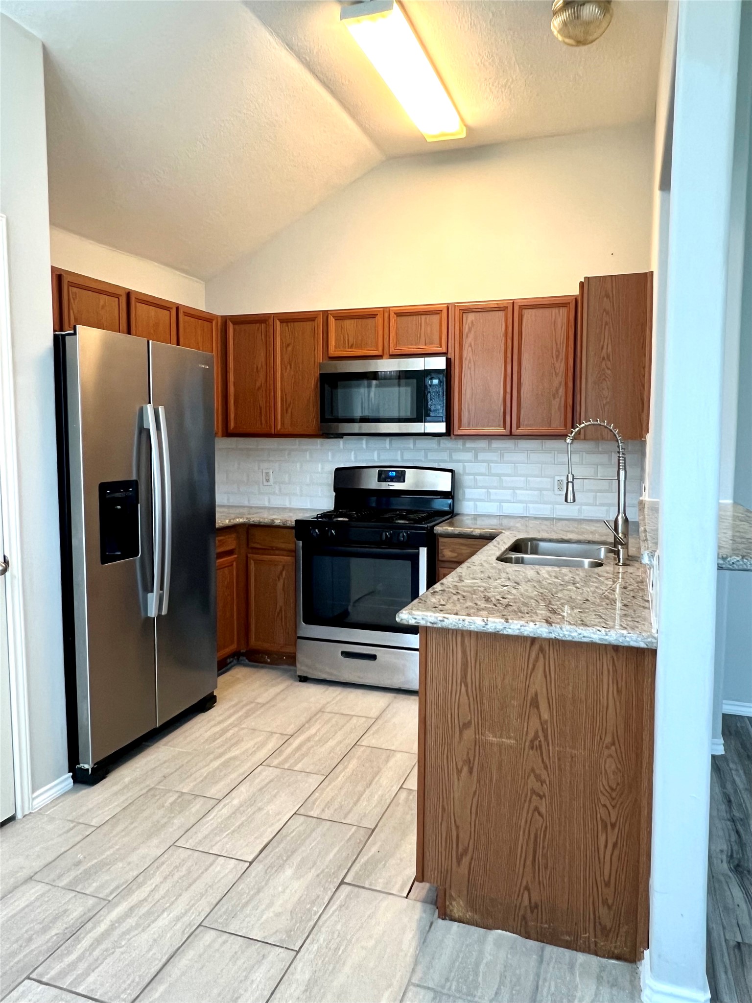 4414 Kulkarni Street Houston, TX 77045 - Photo 11 of 18 a kitchen with stainless steel appliances a stove a sink a microwave a refrigerator and cabinets