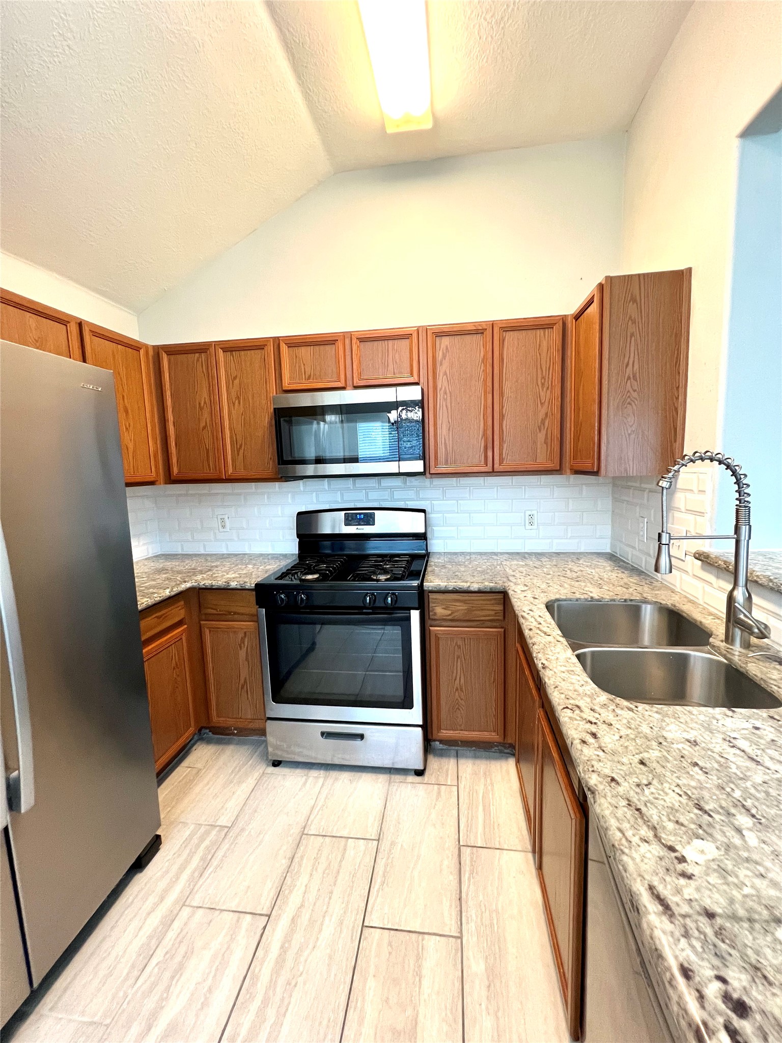 4414 Kulkarni Street Houston, TX 77045 - Photo 12 of 18 a kitchen with stainless steel appliances granite countertop a sink and a stove