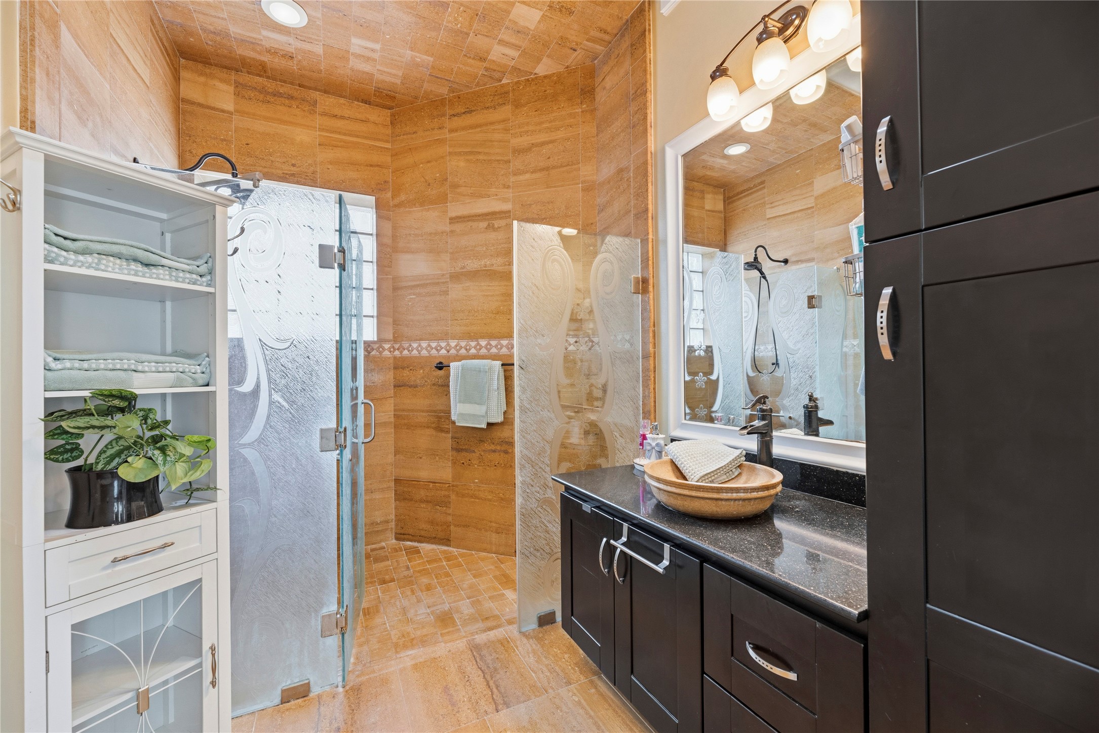 6306 Farm To Market 359 Fulshear, TX 77441 - Photo 26 of 44 Detailed with glass shower doors, this secondary bathroom provides a high-end experience with professional lighting and ample custom cabinetry, perfectly blending luxury with functional storage.