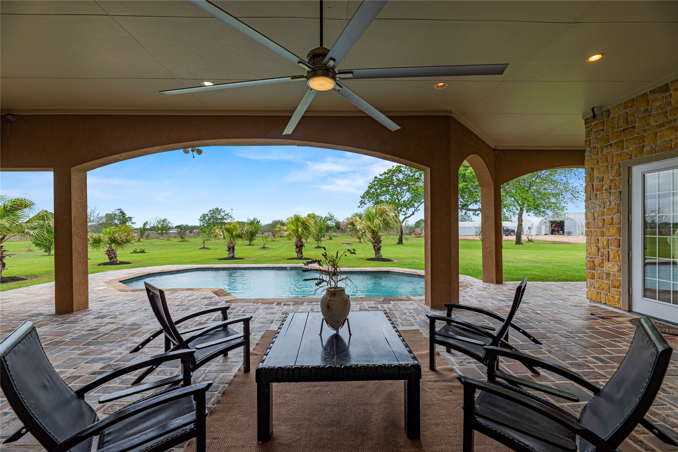 6306 Farm To Market 359 Fulshear, TX 77441 - Photo 28 of 44 Overlooking the sparkling pool and lush acreage, this expansive shaded retreat offers multiple seating areas, creating the perfect outdoor haven for relaxation and effortless entertaining.