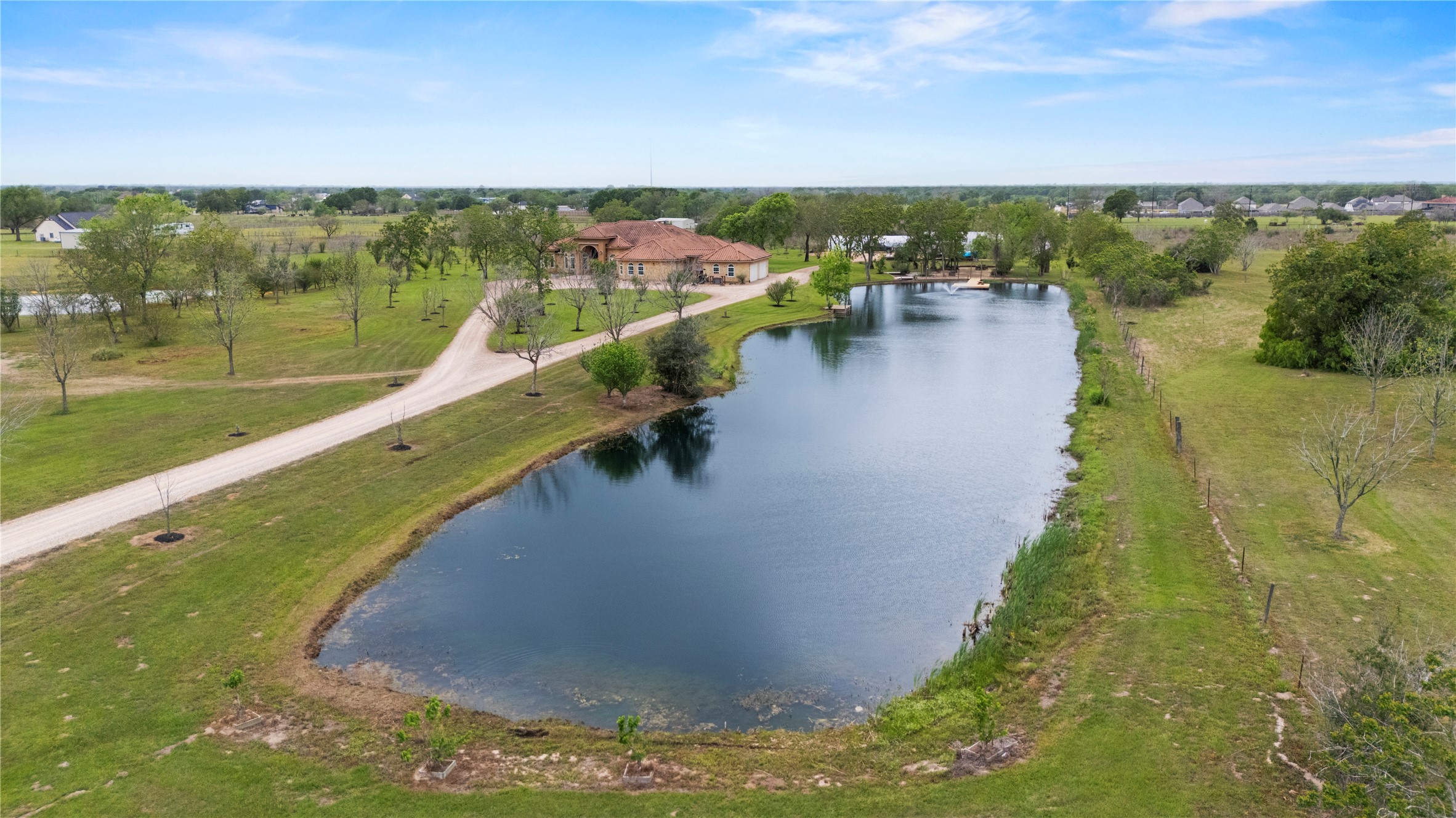 6306 Farm To Market 359 Fulshear, TX 77441 - Photo 40 of 44 This aerial viewpoint showcases the home's thoughtful positioning, emphasizing its privacy while highlighting the harmonious integration of the manicured yard, the lake, and the natural landscape.