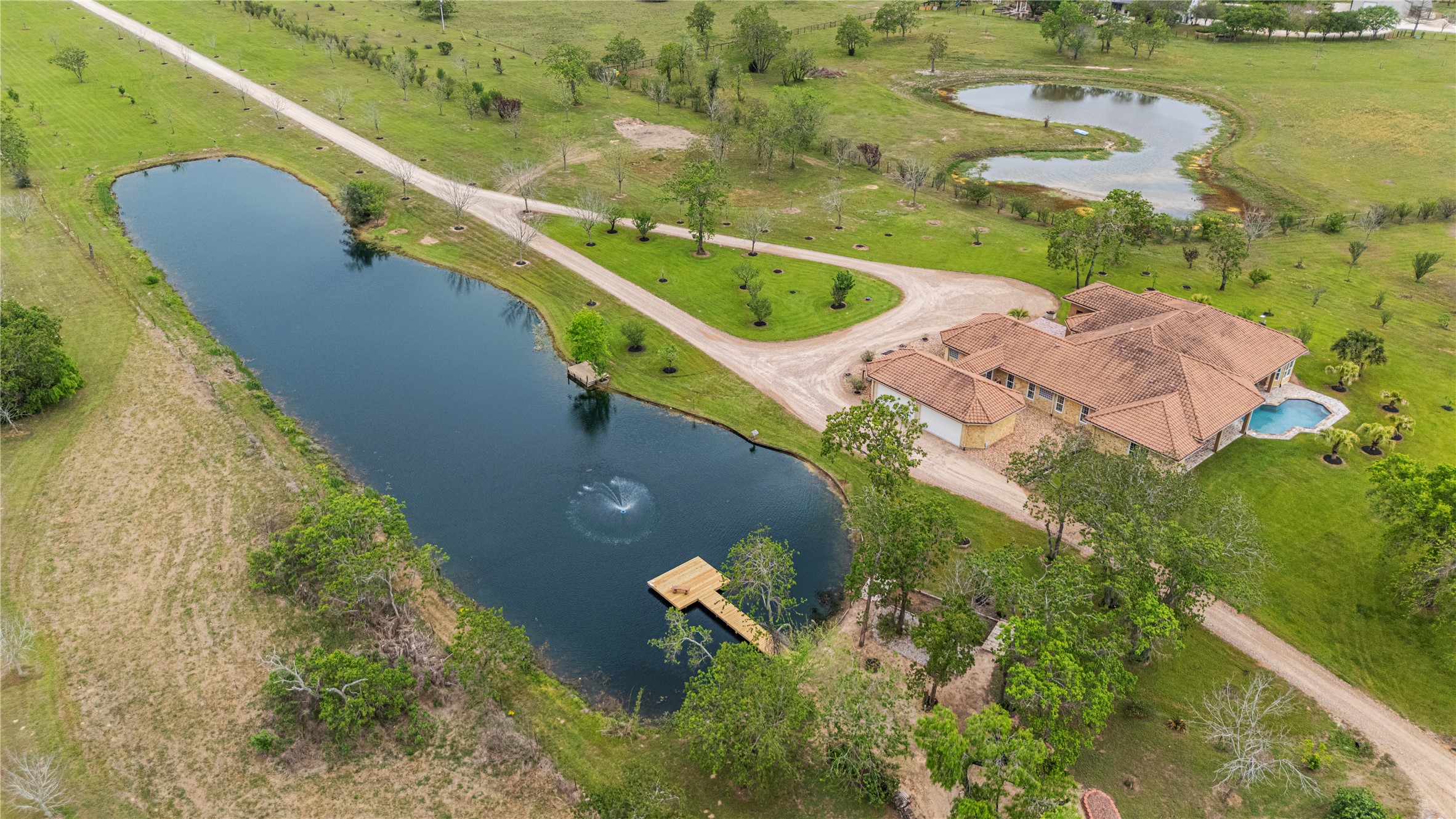 6306 Farm To Market 359 Fulshear, TX 77441 - Photo 41 of 44 This sweeping panorama captures the full breadth of the estate's outdoor amenities, illustrating how the spacious backyard, custom gunite pool, and lake converge to create an unrivaled private sanctuary for relaxation and grand entertaining.