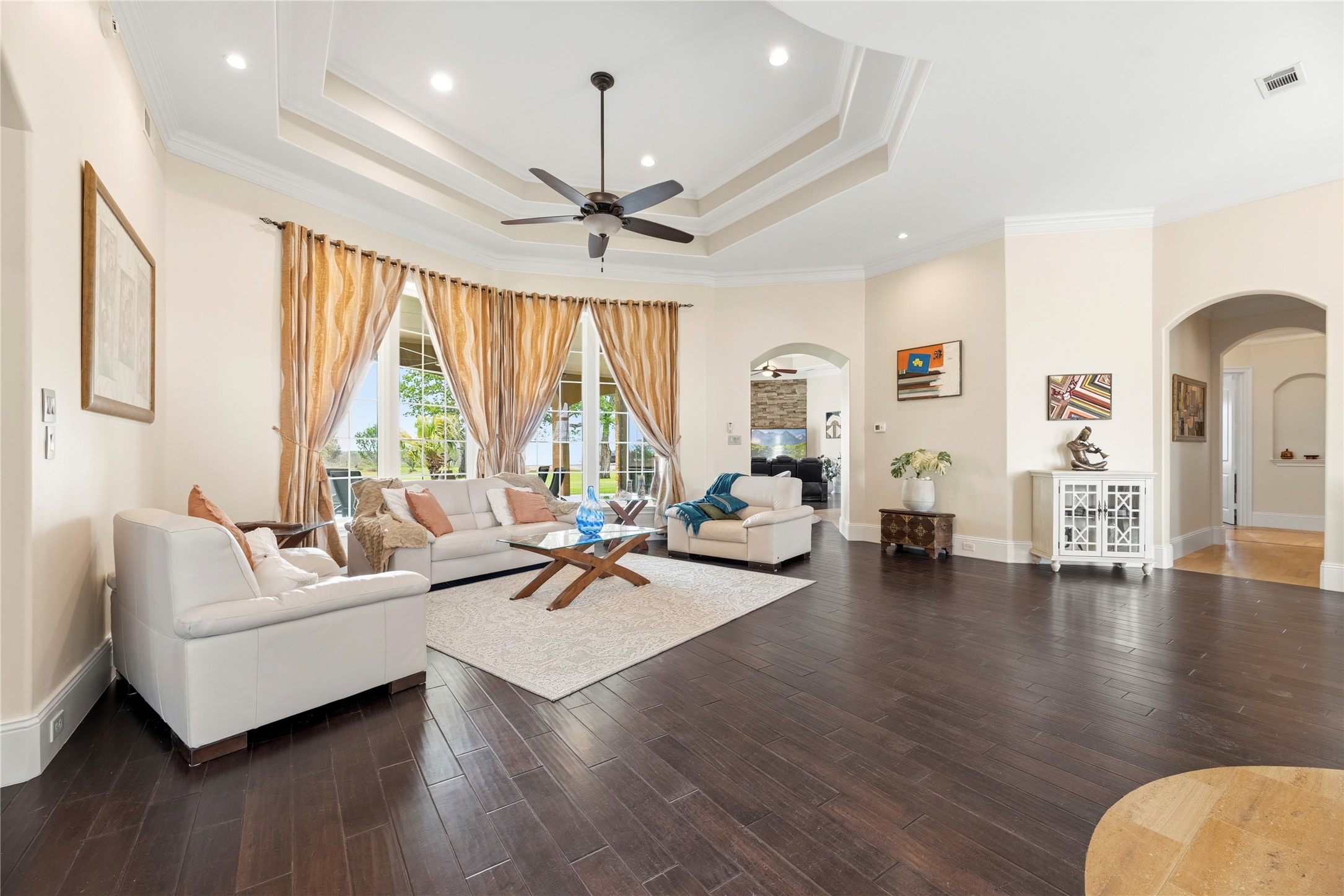 6306 Farm To Market 359 Fulshear, TX 77441 - Photo 9 of 44 Highlighting the estate's architectural depth, this elegant space is defined by a custom tray ceiling and a wall of windows that flood the room with natural light while providing a picturesque frame of the private grounds.