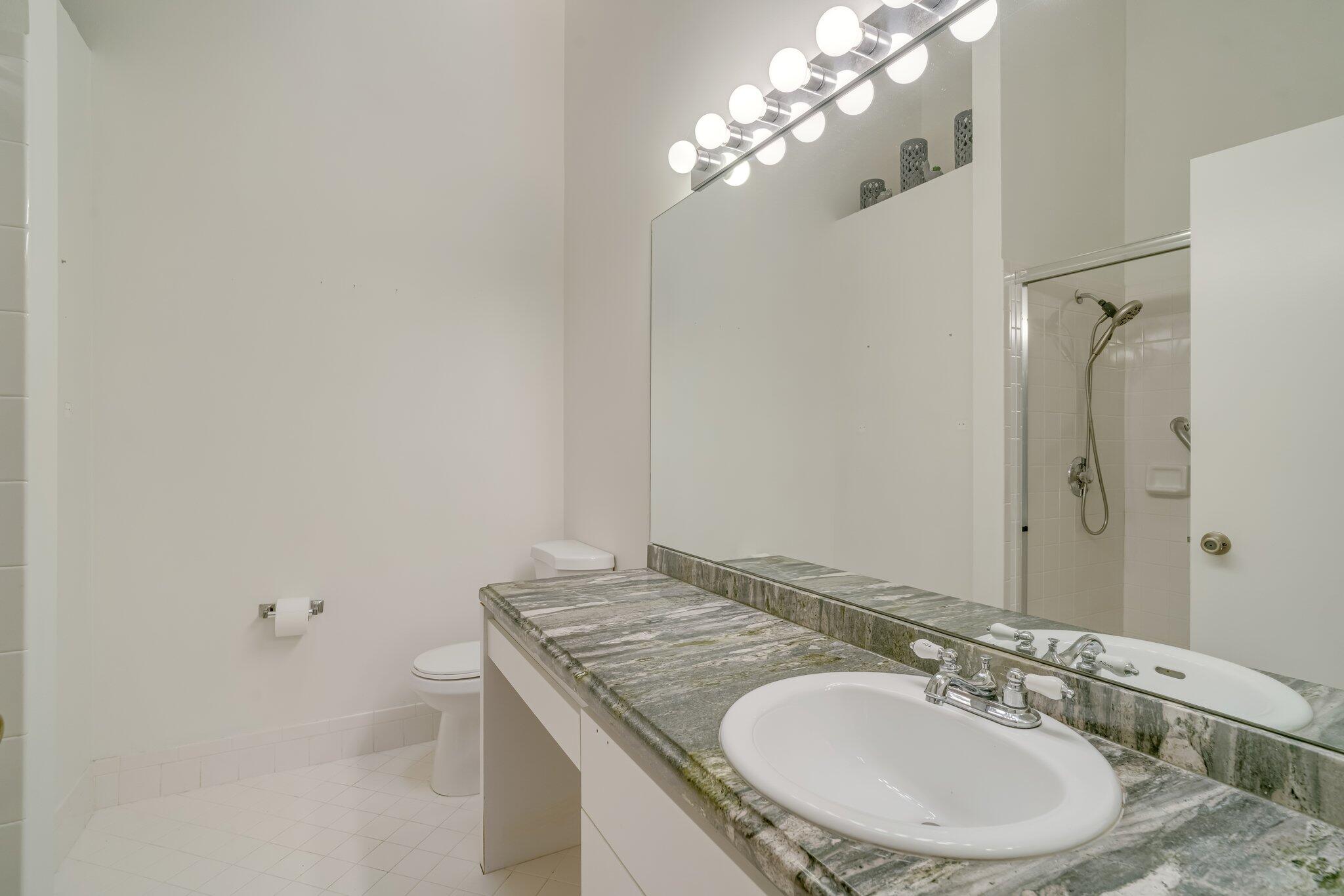 6209 Pond Tree Court Greenacres, FL 33463 - Photo 23 of 38 a bathroom with a granite countertop sink a toilet and a mirror