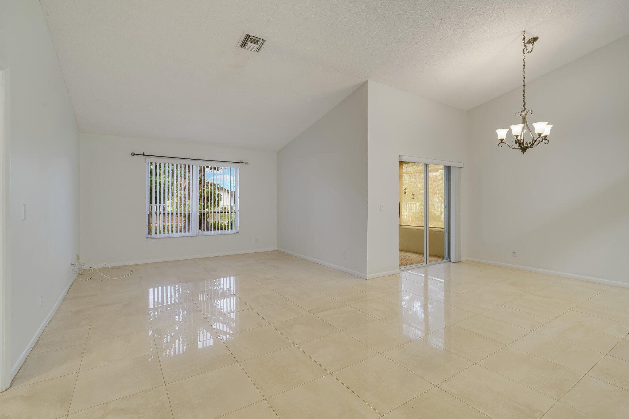 6209 Pond Tree Court Greenacres, FL 33463 - Photo 4 of 38 an empty room with windows and chandelier fan
