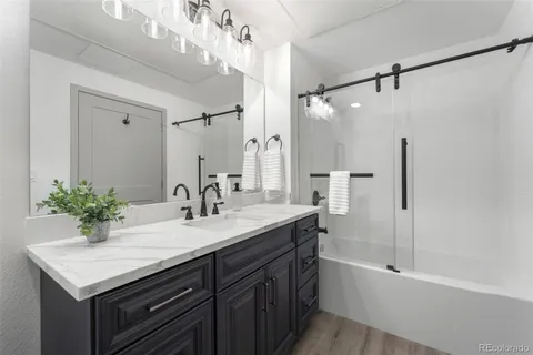 a bathroom with a sink double vanity granite tub shower and a mirror