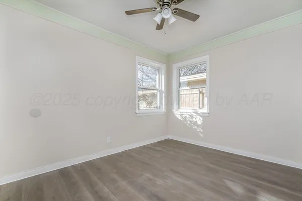 a view of empty room with wooden floor and fan