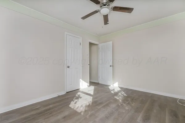 an empty room with wooden floor and fan