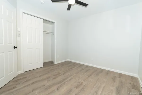 an empty room with a ceiling fan and wooden floor