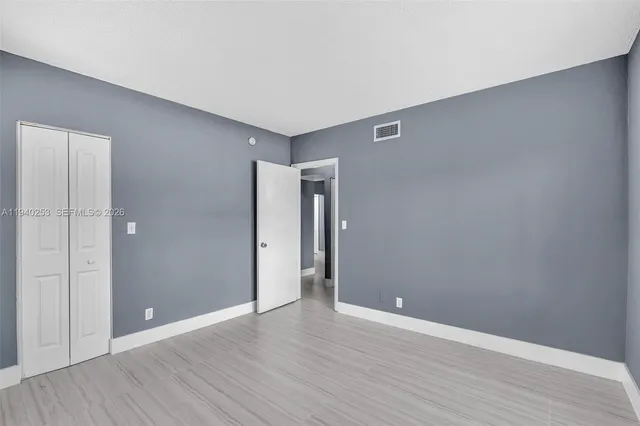 a view of an empty room with wooden floor and closet