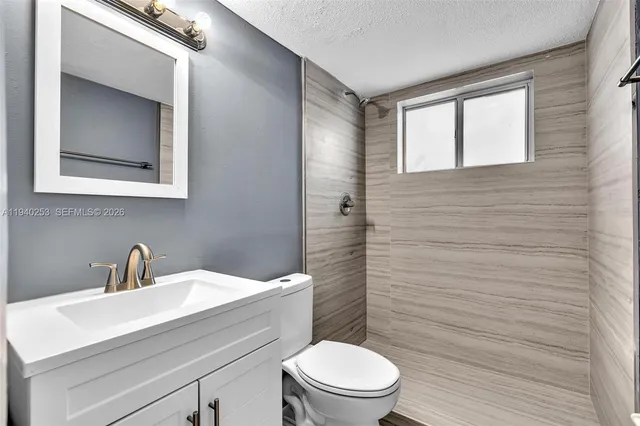 a bathroom with a toilet a sink a mirror and vanity