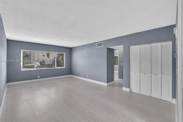 a view of an empty room with wooden floor and window