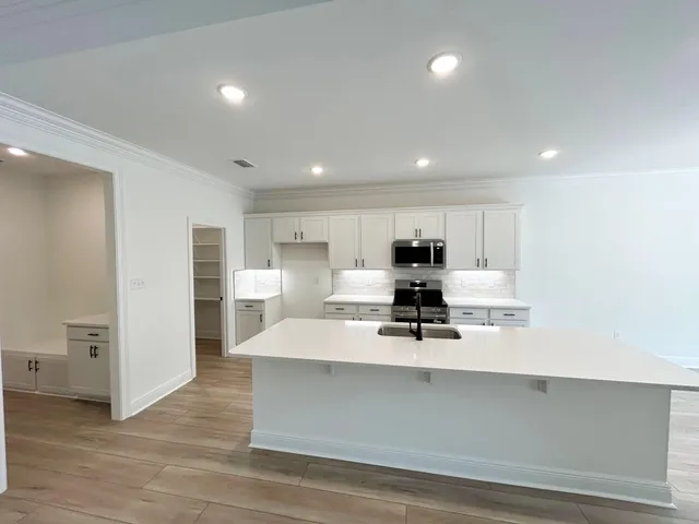 a large white kitchen with kitchen island a sink a stove and refrigerator