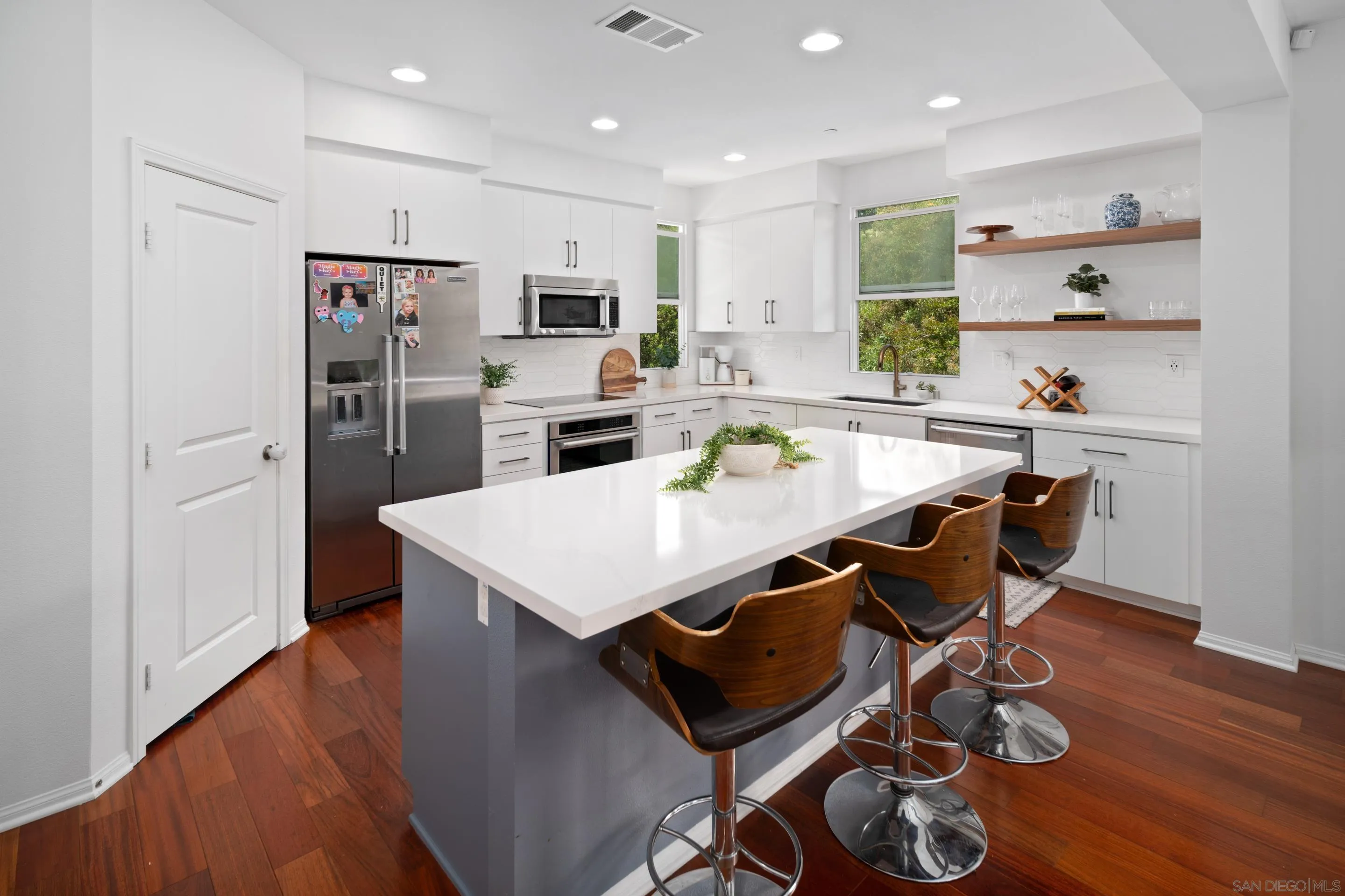 1879 Black Mustard Lane Carlsbad, CA 92011 - Photo 2 of 24 a kitchen with stainless steel appliances a dining table chairs refrigerator and microwave