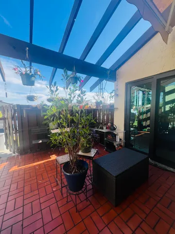a living room with patio furniture and potted plants