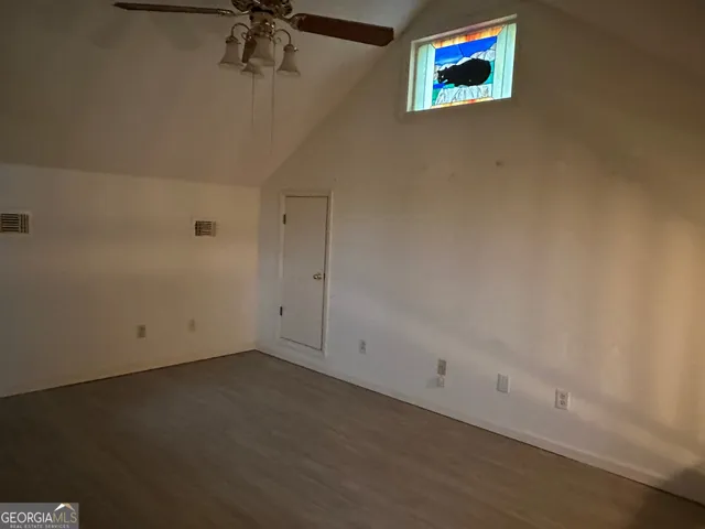 an empty room with a ceiling fan and a window