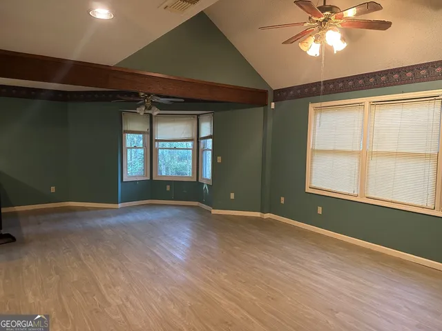a view of an empty room with a window and wooden floor