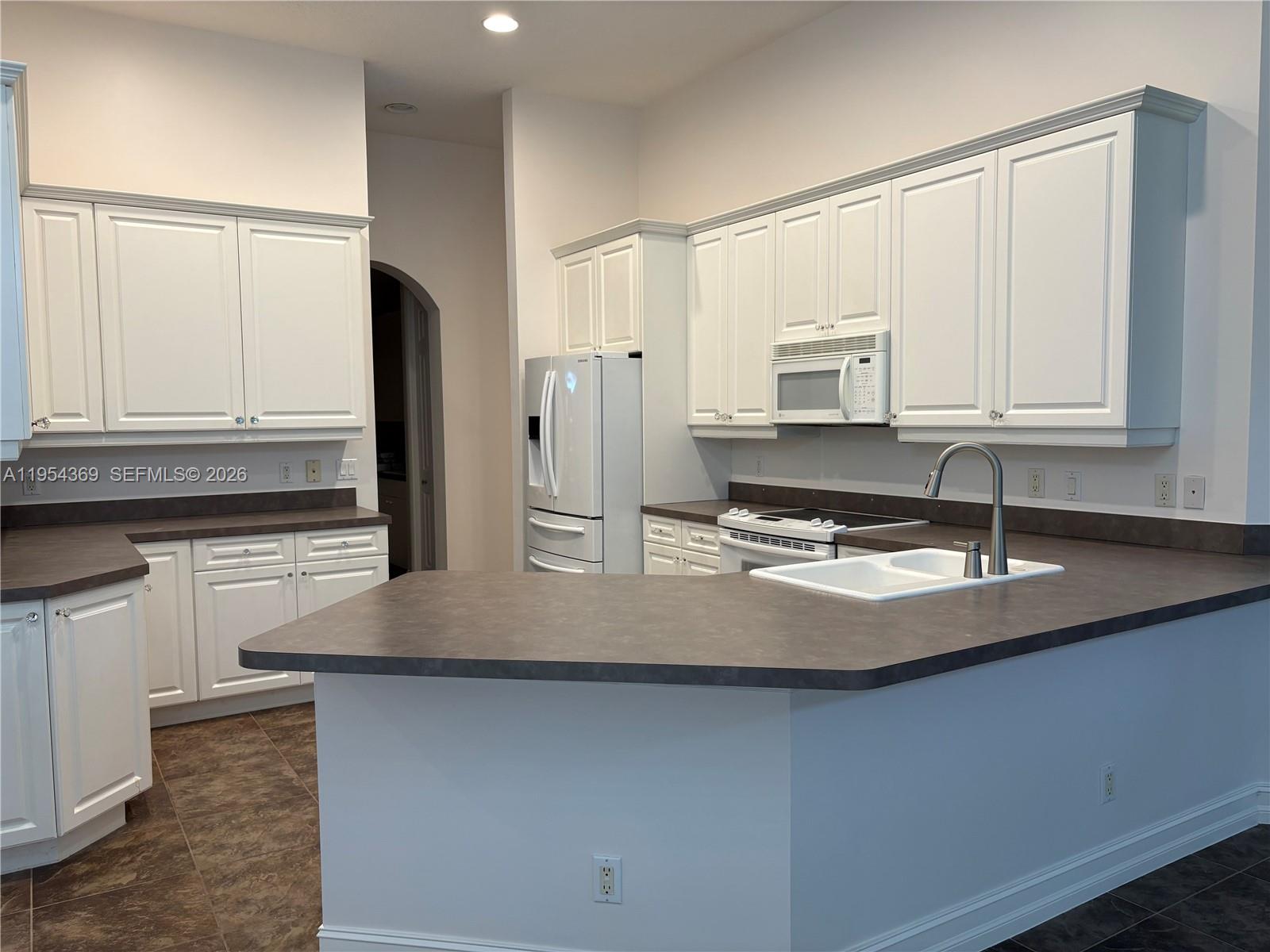 18265 Southeast Ridgeview Drive Tequesta, FL 33469 - Photo 3 of 12 a kitchen with stainless steel appliances granite countertop a sink a stove and white cabinets
