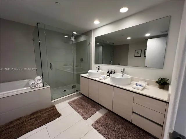 a bathroom with a double vanity sink mirror and bathtub