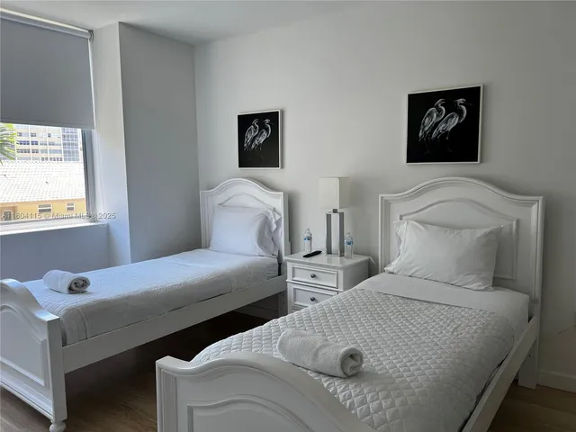 a bedroom with two beds and painting on the wall