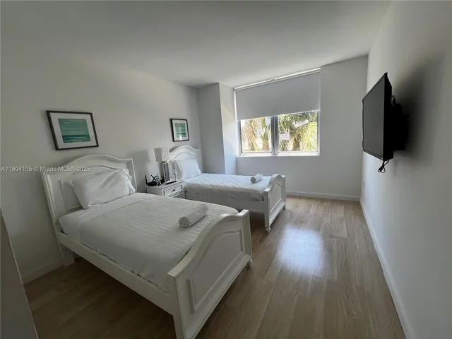 a hotel room with two bed and a flat screen tv