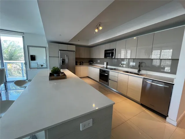 a kitchen with stainless steel appliances a sink a stove a microwave a refrigerator a stove and cabinets