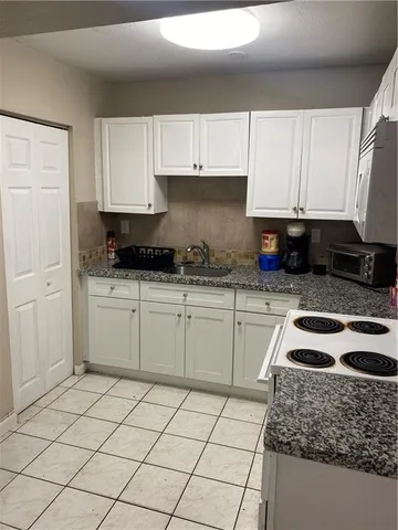 a kitchen with granite countertop white cabinets and white appliances