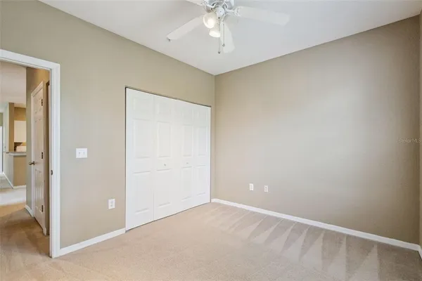 an empty room with a chandelier fan and closet area