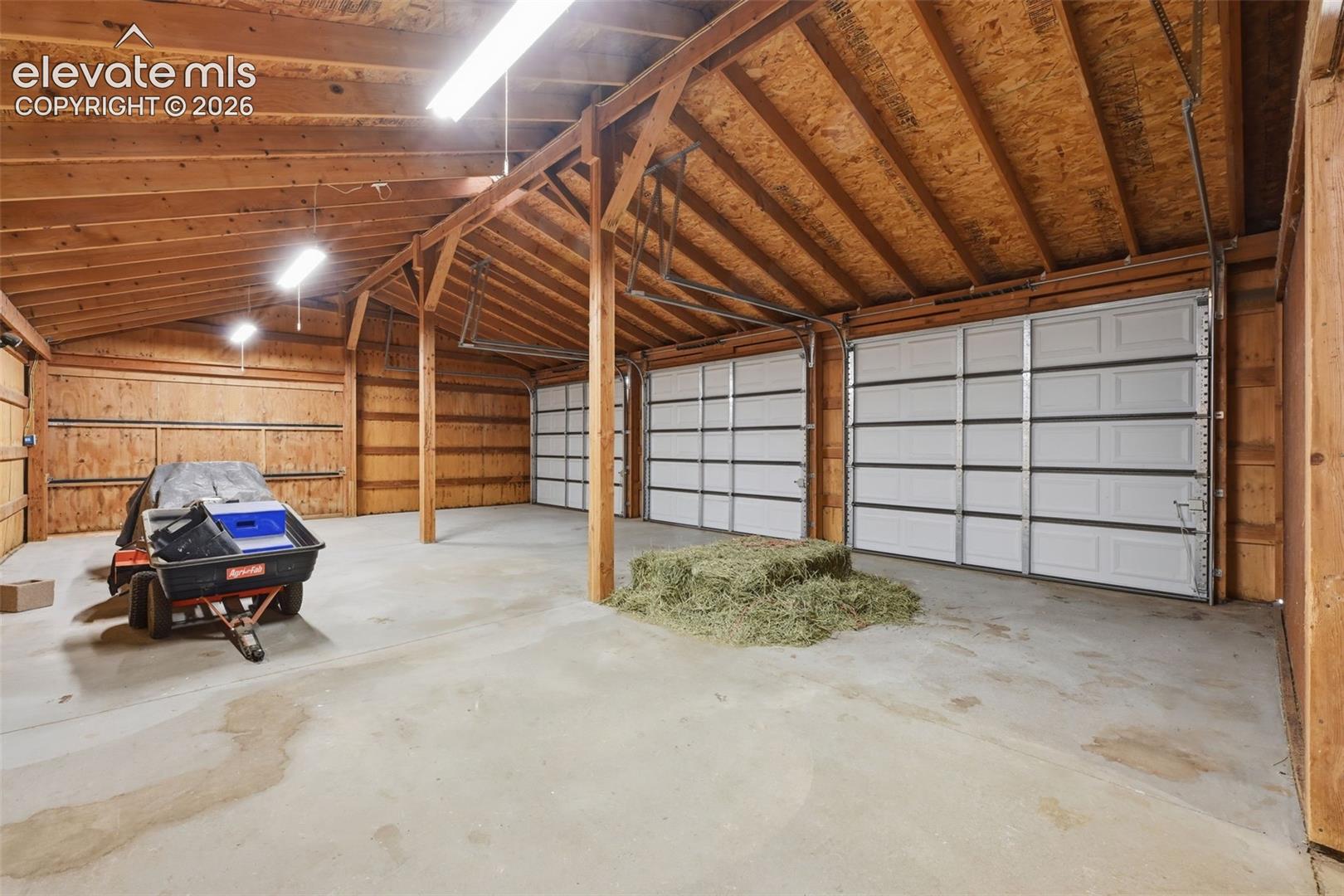 6015 West Condor Road Peyton, CO 80831 - Photo 42 of 50 Spacious outbuilding featuring concrete flooring, exposed wood beam ceiling, wood plank walls, and multiple overhead garage doors