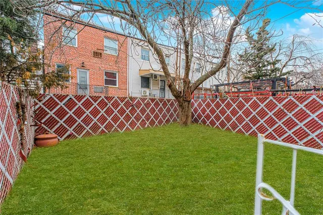 a view of a backyard with wooden fence and a large tree