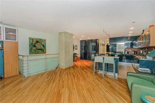 a kitchen with stainless steel appliances kitchen island granite countertop a refrigerator a stove top oven and couches chairs