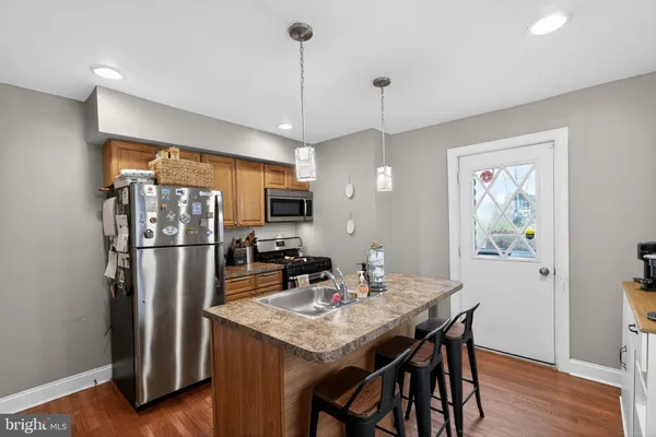 a kitchen with stainless steel appliances granite countertop a refrigerator a sink a stove a dining table and chairs