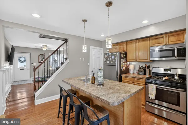 a kitchen with stainless steel appliances granite countertop a stove a refrigerator a kitchen island a table and chairs