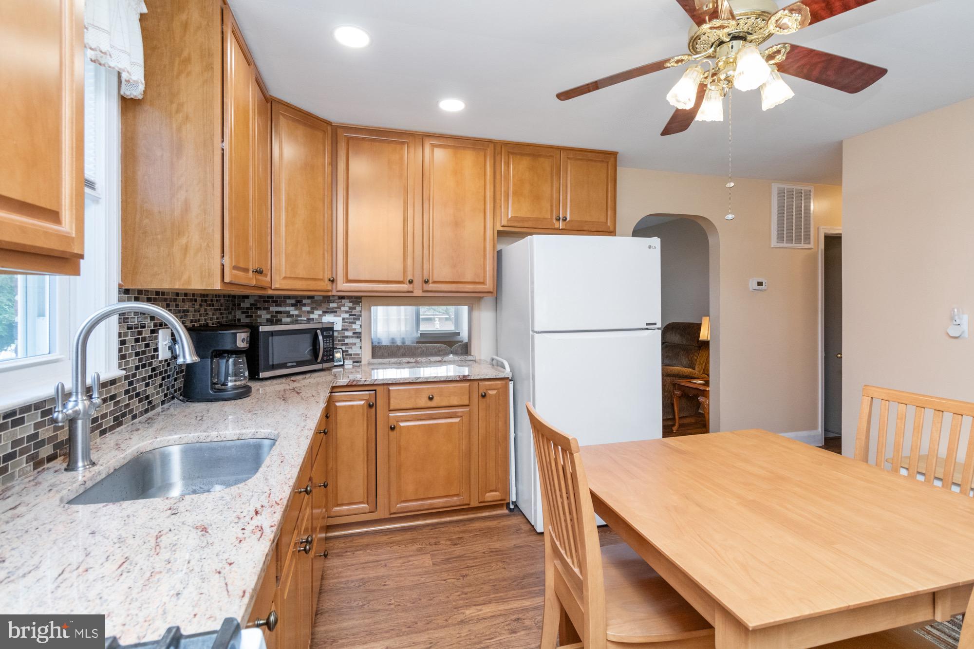 4305 Fullerton Avenue Baltimore, MD 21206 - Photo 12 of 36 a kitchen with stainless steel appliances granite countertop a refrigerator a sink dishwasher a stove with wooden cabinets and floor