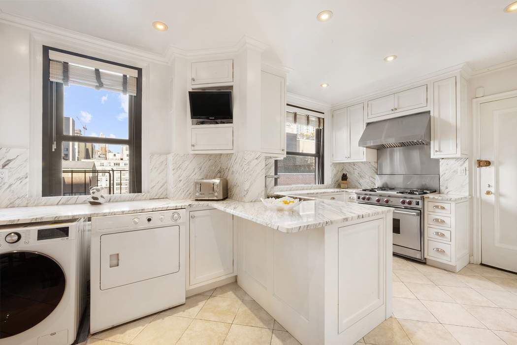 215 East 72nd Street, Unit 9W Manhattan, NY 10021 - Photo 11 of 15 a kitchen with white cabinets sink and white appliances