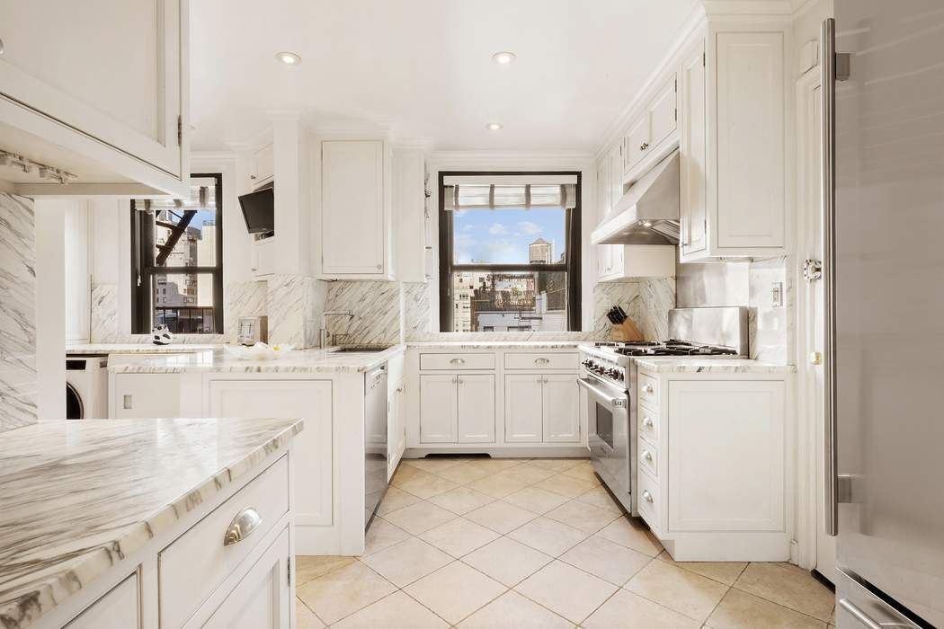 215 East 72nd Street, Unit 9W Manhattan, NY 10021 - Photo 9 of 15 a kitchen with white cabinets and white appliances