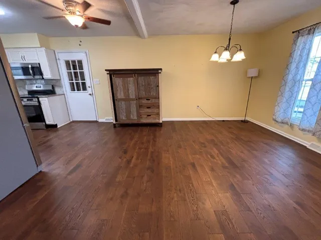 a kitchen with stainless steel appliances granite countertop a refrigerator a stove a sink and white cabinets with wooden floor