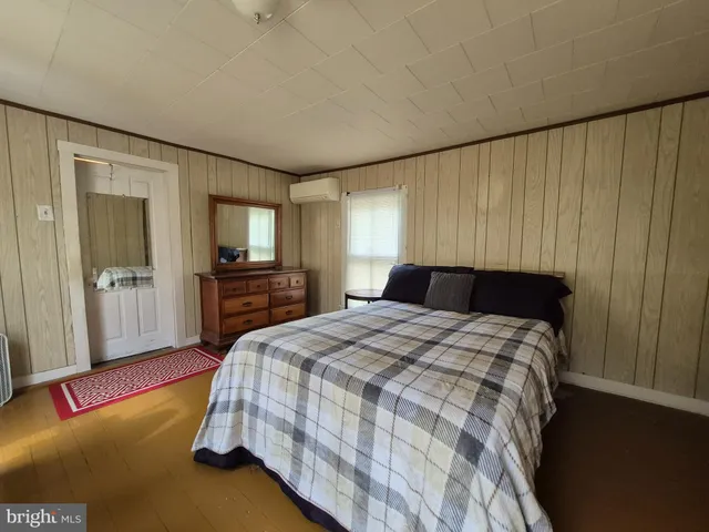 a bed sitting in a spacious bedroom next to a window and a flat screen tv