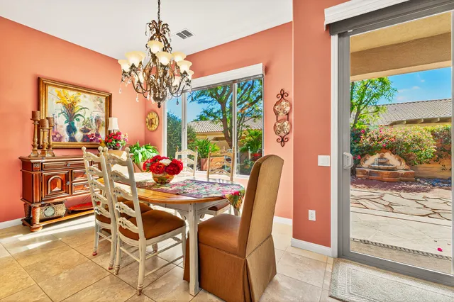 a view of a dining room with furniture a chandelier and large windows