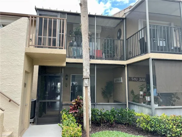 a view of yellow house with a large windows and flower plants